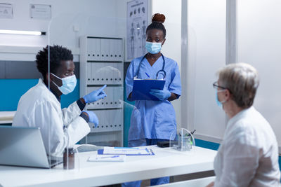 Doctor and nurse wearing mask talking with patient