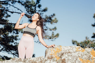 Portrait of young woman standing against sky