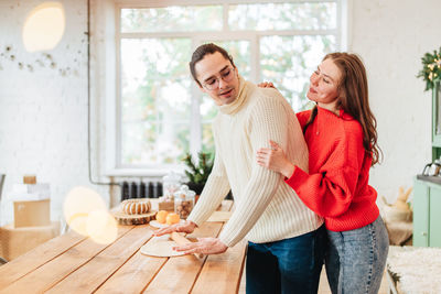 Young man and woman romantic couple couple hug at the kitchen while coocking and backing