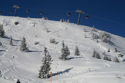 Scenic view of snow covered mountains against blue sky