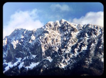 Scenic view of snow covered mountains against cloudy sky