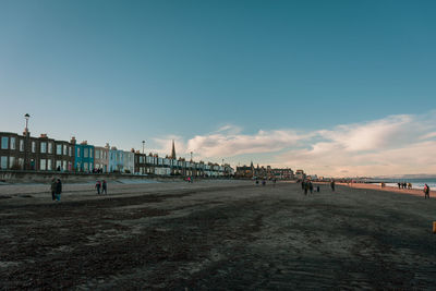 People on beach against sky in city
