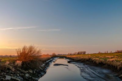 River alongside landscape against sky