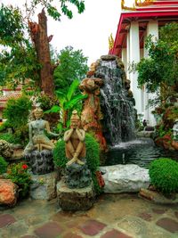 Statue by fountain against trees and plants