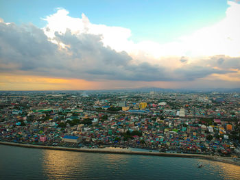 High angle view of townscape by sea against sky during sunset