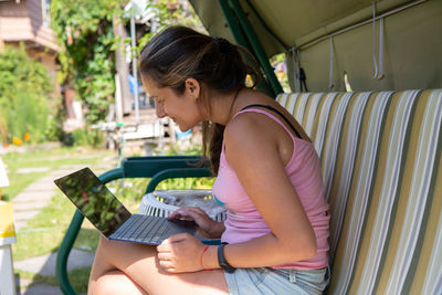 Beautiful girl working on computer in the swing. the distance learning