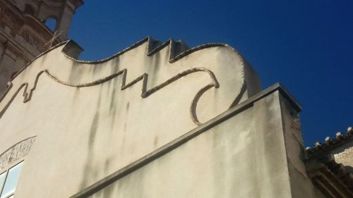 Low angle view of text on building against clear sky