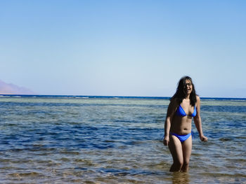 Full length of woman standing on beach against clear sky