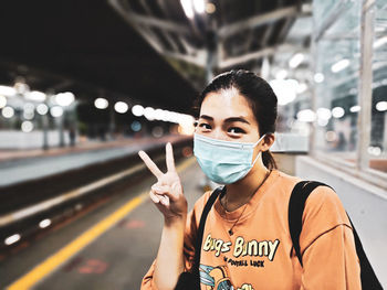 Portrait of young woman standing on illuminated bus