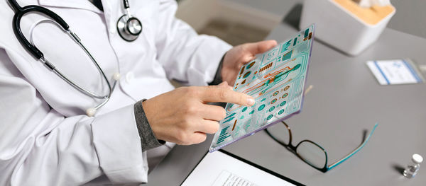 Female doctor touching transparent tablet with medical digital diagnostic on screen