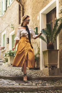 Portrait of young woman standing against building