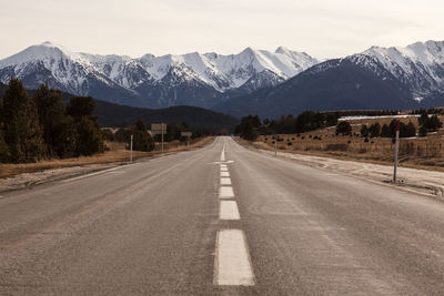 Road leading towards mountains against sky