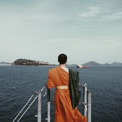 Rear view of man looking at sea against sky