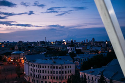 High angle view of buildings in city against cloudy sky at dusk