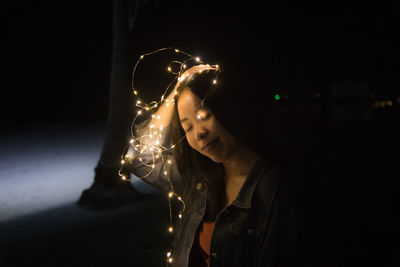 Young woman looking at illuminated lights at night