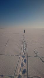 Tire tracks on snow landscape against sky