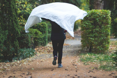 Rear view of man walking on street during rainy season