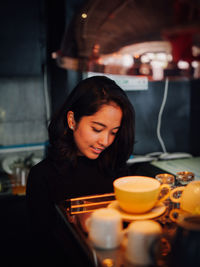 Young woman holding drink in glass on table