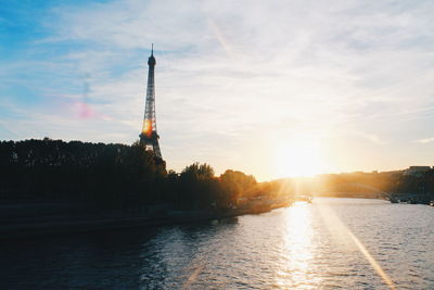 View of eiffel tower by river during sunset