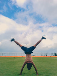 Full length of man jumping on field against sky