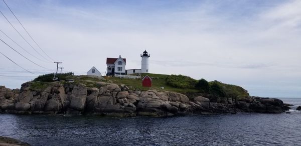 Lighthouse by sea against sky