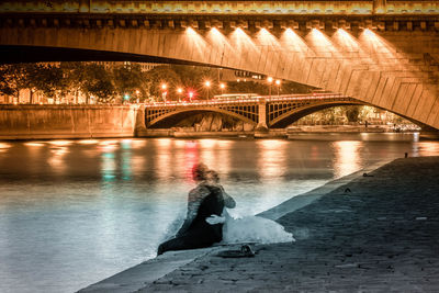 Illuminated bridge over river in city at night