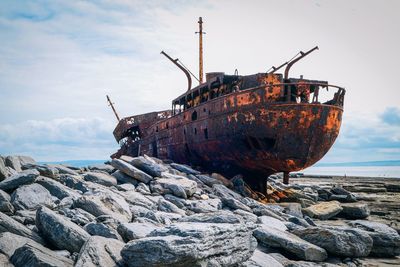 Abandoned boat on shore against sky