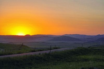 Scenic view of field against orange sky