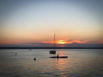 Silhouette of boats floating on water at dusk