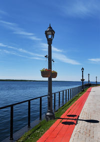 Street light by sea against sky