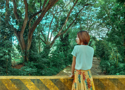 Young woman standing against trees