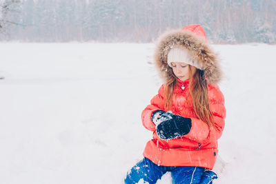 Portrait of smiling young woman standing on snow covered field