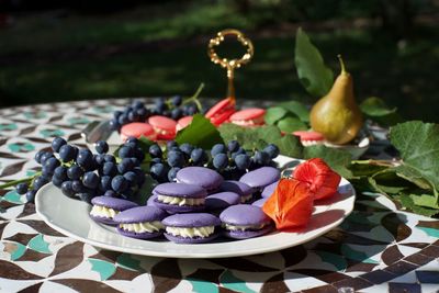 Close-up of macaroons and fruits in plate on table