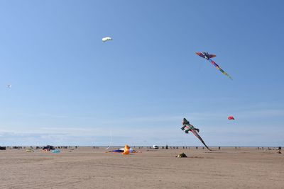 People jumping on beach against blue sky