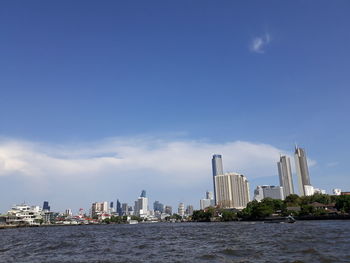 Sea by modern buildings against sky in city