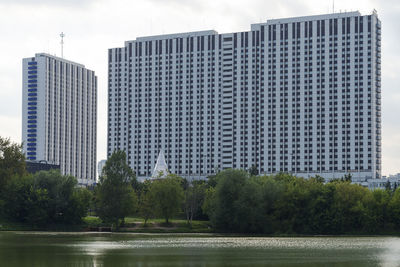 Modern buildings by river against sky in city