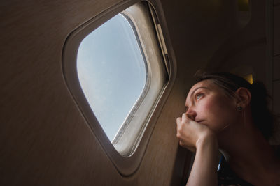 Sad woman at porthole in plane