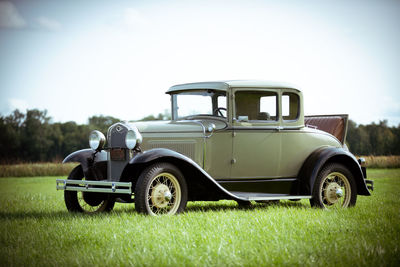 Vintage car on field against sky