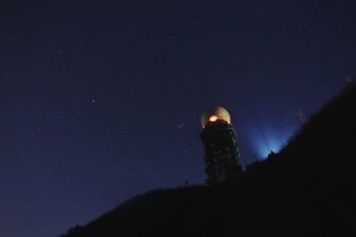 Low angle view of tower on silhouette mountain against sky at night