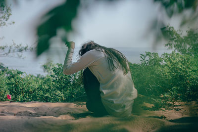 Side view of woman sitting on field