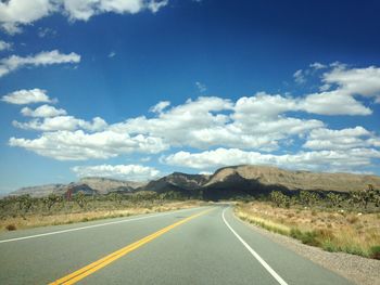 Road by mountains against blue sky