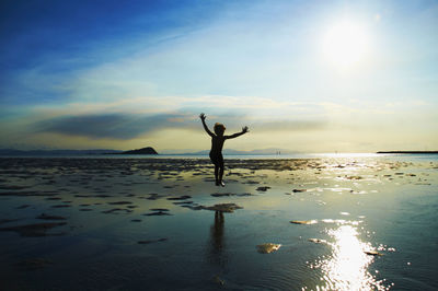 Silhouette person on beach against sky during sunset