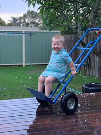 Baby boy standing on hand truck and smiling