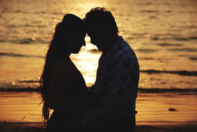 Silhouette people at shore during sunset