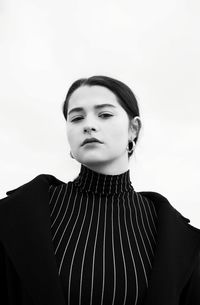 Portrait of young woman looking away against clear sky