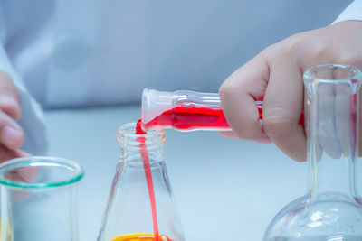 Midsection of scientist doing experiment with liquids in laboratory 