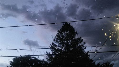 Low angle view of power lines against cloudy sky