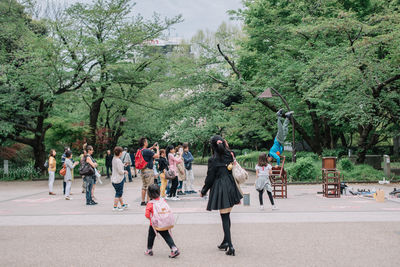 Group of people walking on road along trees