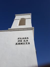 Low angle view of text on building against clear blue sky