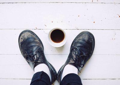 Low section of person standing by coffee cup on floor